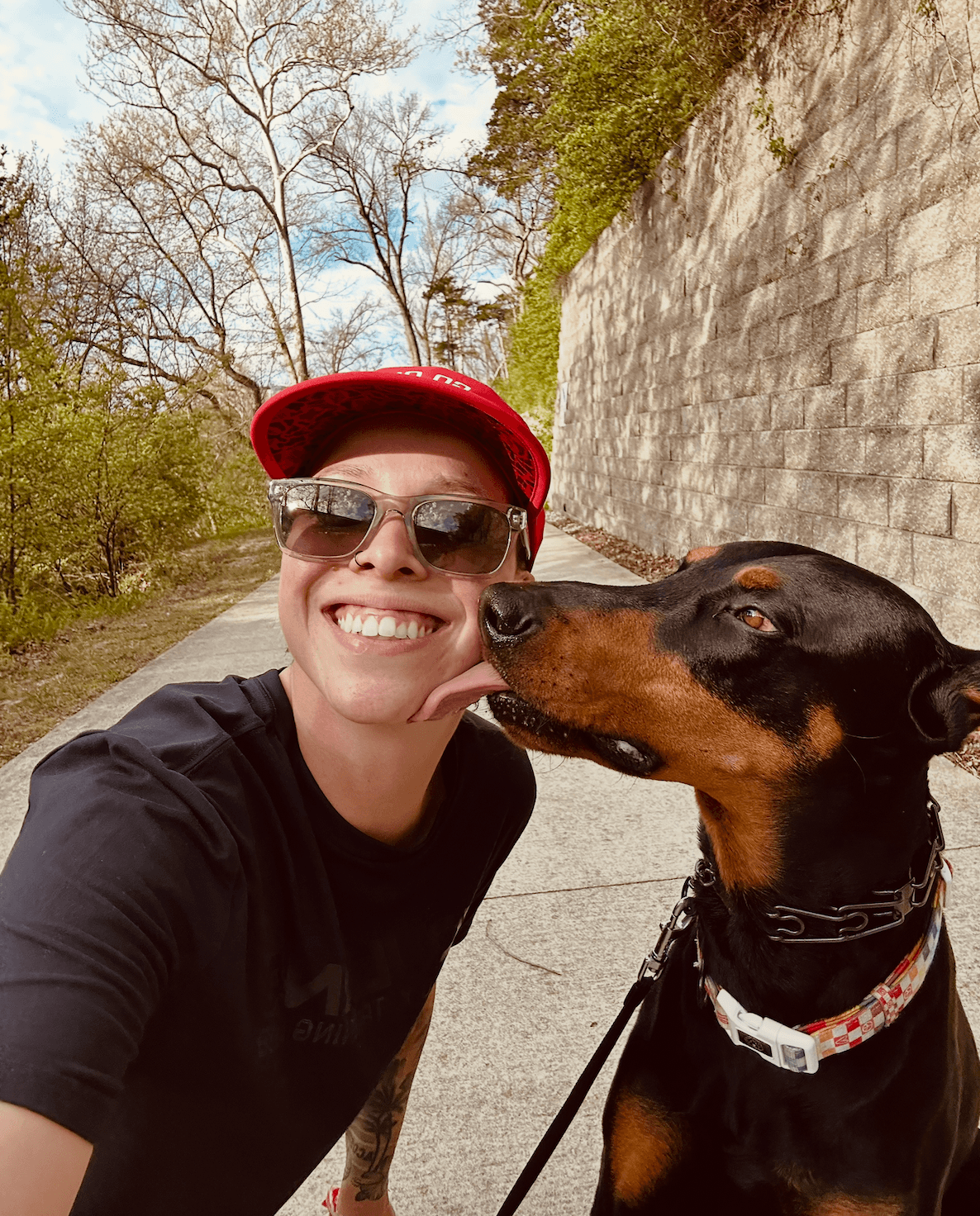 A Run Bud owner getting a kiss from their Doberman on a trail